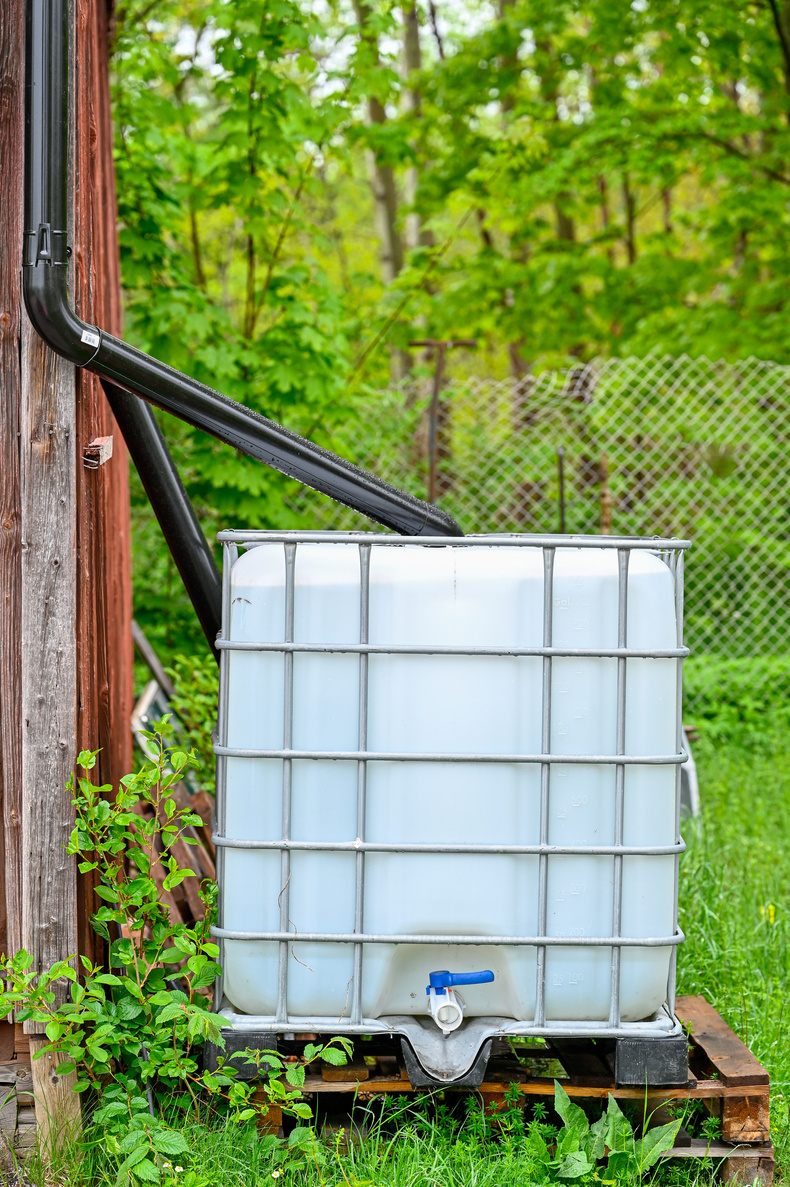 cubic tank full of rainwater near red barn